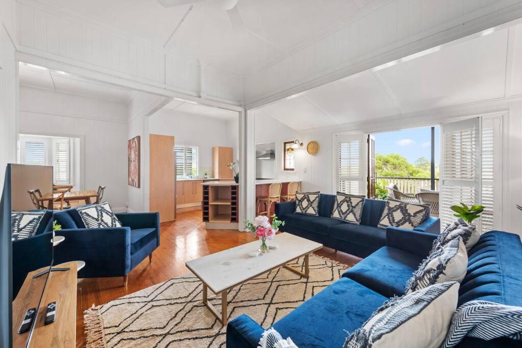 a living room with blue couches and a table at Charming 5BR Family Home w/Pool 10min from Airport in Brisbane