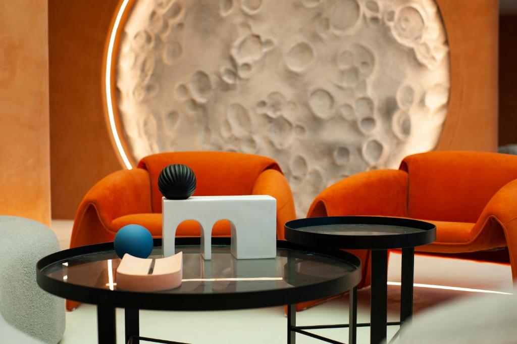 a coffee table in front of two orange chairs at Dream Designer Hotel - Huimin Street Branch of Xi'an Bell and Drum Tower in Xi'an