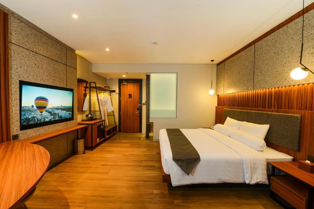 a hotel room with a bed and a flat screen tv at Nata Azana Hotel Solo in Solo