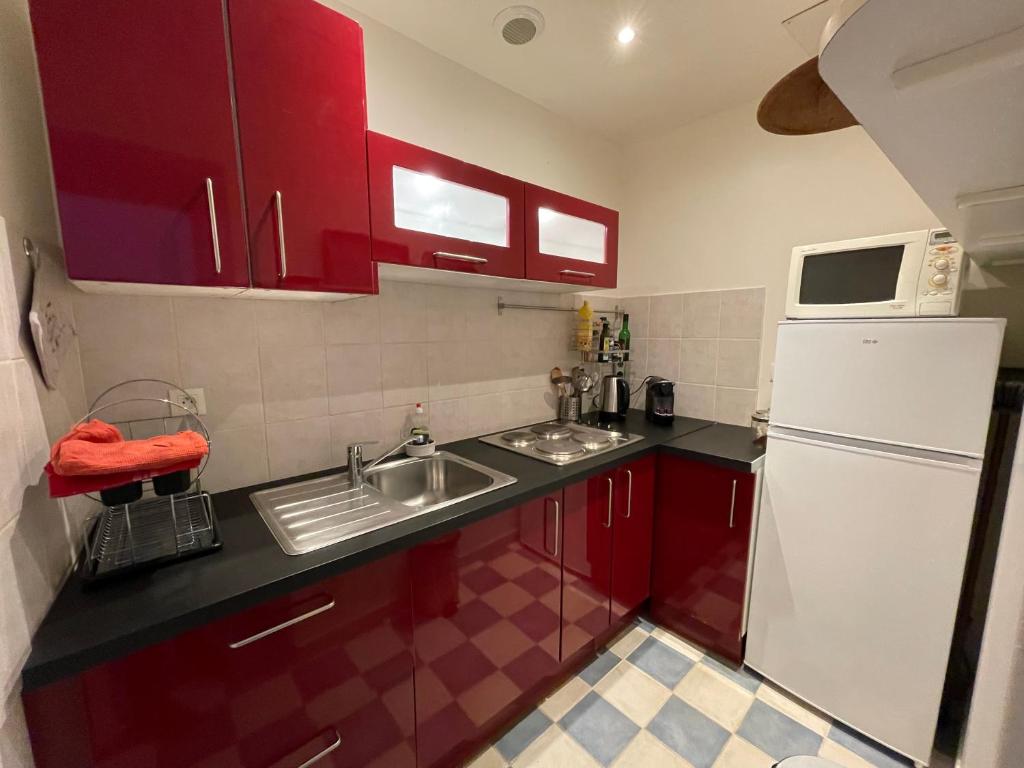 a kitchen with red cabinets and a white refrigerator at Le villequier 8 Rouen centre in Rouen