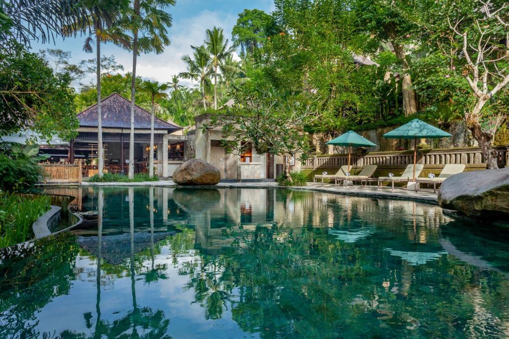 une piscine dans un complexe avec des chaises et un bâtiment dans l'établissement The Lokha Ubud Resort, Villas & SPA, à Ubud