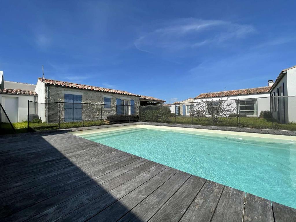 une piscine avec une terrasse en bois et une maison dans l'établissement Grande Villa 5 Ch. avec Piscine Privée, Jardin, Proche Mer et Centre - Classée 3 Étoiles - FR-1-246A-226, à Saint-Denis-dʼOléron