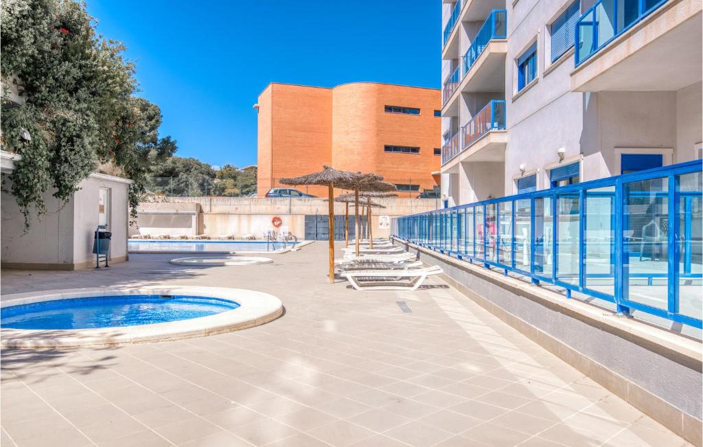a swimming pool with chairs and umbrellas next to a building at Stunning Apartment In Alicante With Outdoor Swimming Pool in Alicante