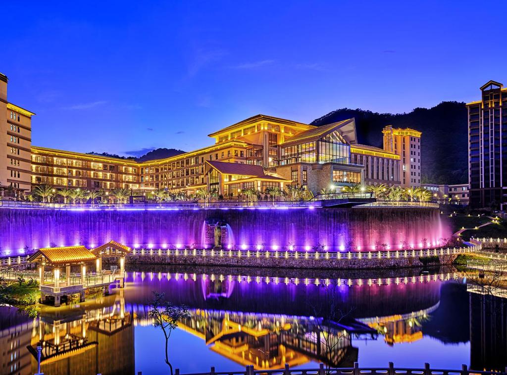 a resort with purple lights on the water at night at Regal Palace DeRUCCI Resort in Huizhou