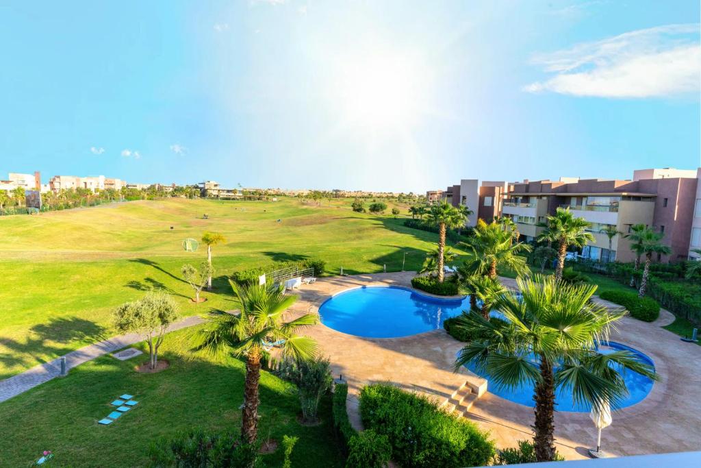 - une vue aérienne sur un complexe avec une piscine et des palmiers dans l'établissement Cozy Golf Apartment Wifi 4k-TV Netflix, à Marrakech