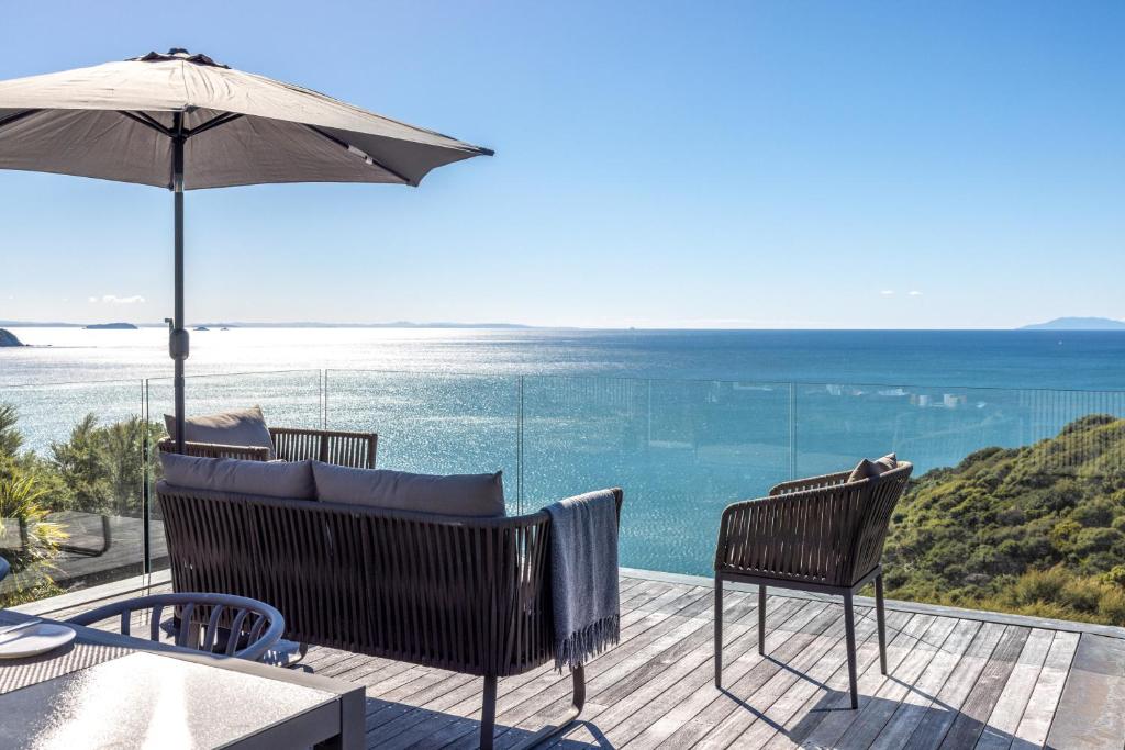 a patio with an umbrella and chairs and the ocean at Bellevue in Onetangi