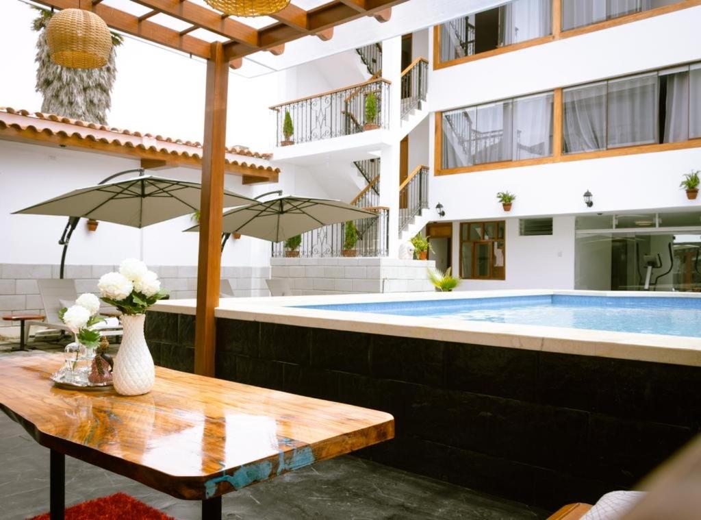 un patio con una mesa de madera y una piscina en Baños del Inca Premium Hotel, en Los Baños del Inca