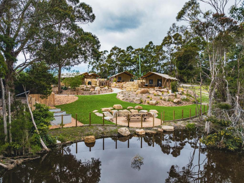 un patio trasero con un estanque y una casa en Glamping 148 Tasmania en St Helens