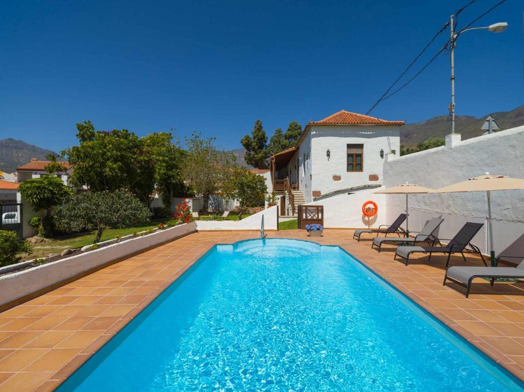 - une piscine avec des chaises et une maison dans l'établissement Casa Rural la Montañeta, à Santa Lucía
