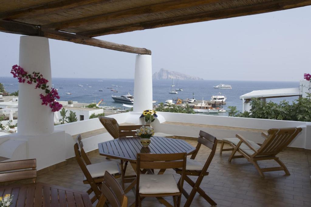 balcón con mesa, sillas y vistas al océano en Hotel Tesoriero en Panarea