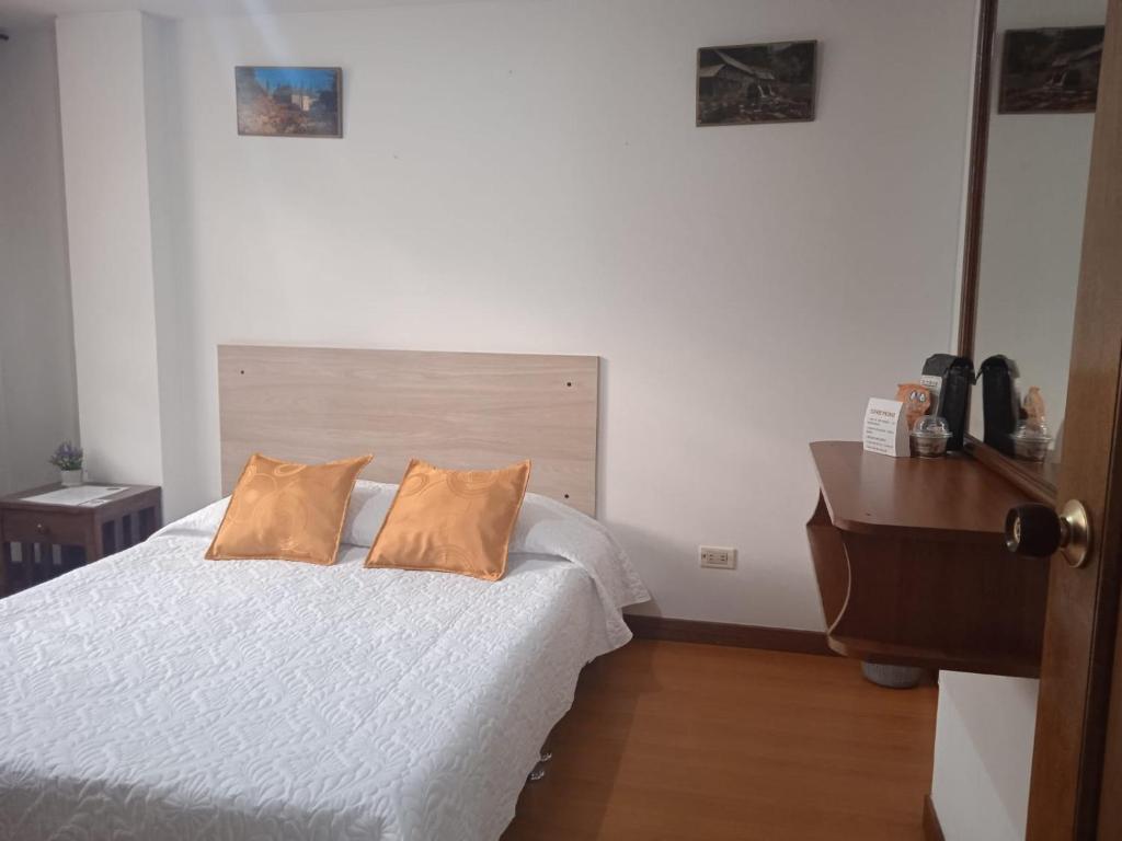 1 dormitorio con 1 cama blanca y 2 almohadas en Habitaciones C&S Bogotá, en Bogotá