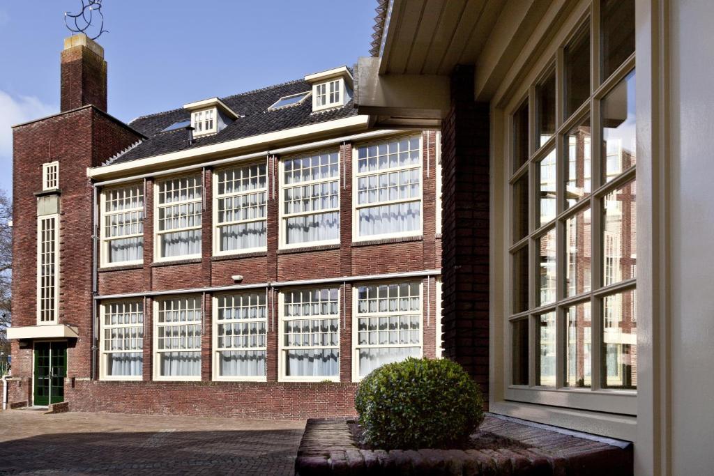 a large brick building with windows and a plant in front at College Hotel Alkmaar in Alkmaar