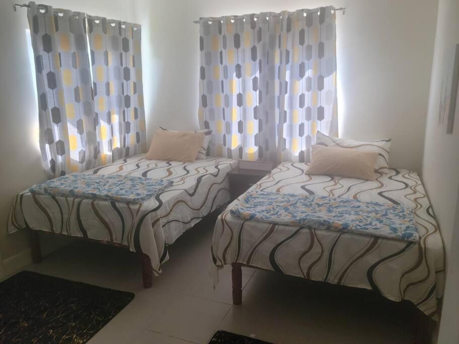 two twin beds in a room with curtains at Le-Rendezvous A Charming 2 Bedroom 2 Bath home in Lucea