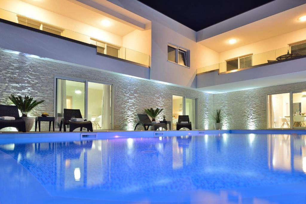 - une piscine dans une maison avec des chaises et des tables dans l'établissement Luxury Apartments Marija, à Sukošan