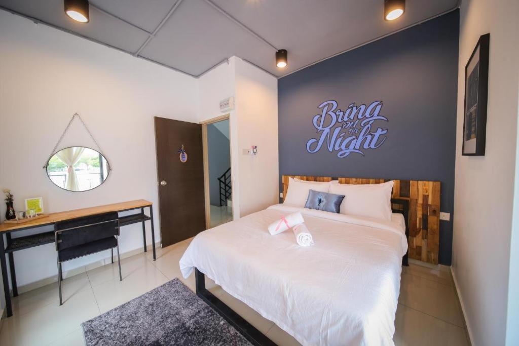 a bedroom with a bed with a desk and a sign on the wall at Pondok Tok Bee in Bayan Lepas