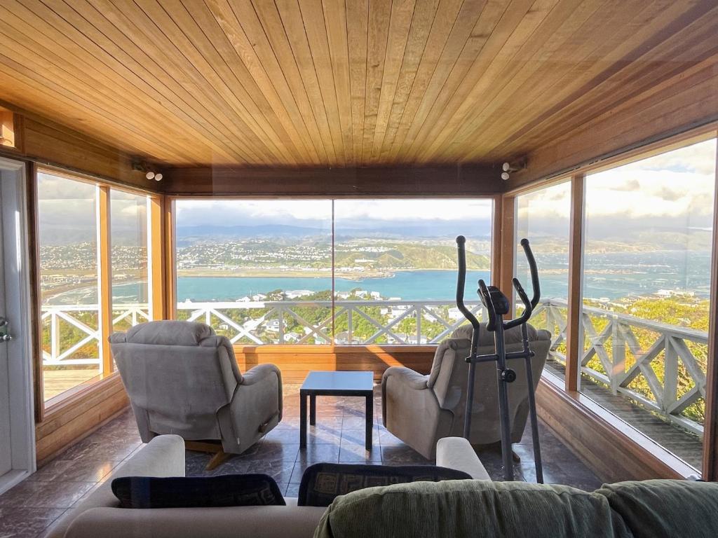 een woonkamer met een bank en stoelen en een groot raam bij NO PARTY ALLOWED,Sea view 5 bedroom house in Wellington