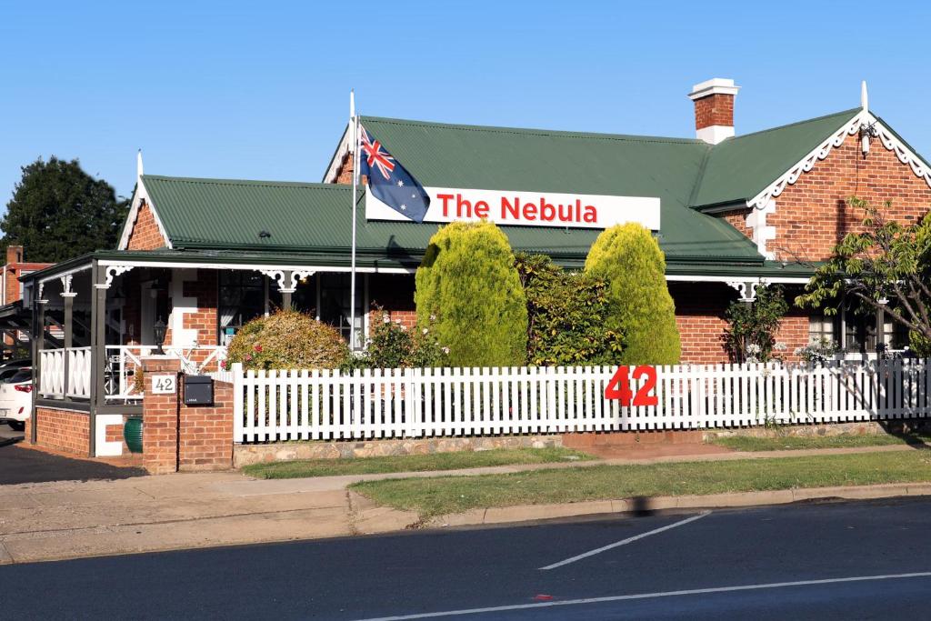 a restaurant with a white fence in front of a building at Nebula Motel in Cooma