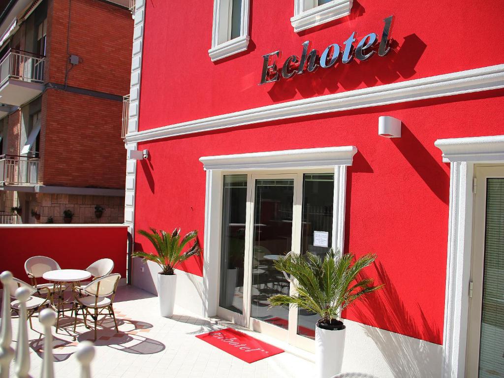 un edificio rosso con tavolo e sedie all'esterno di Echotel a Porto Recanati