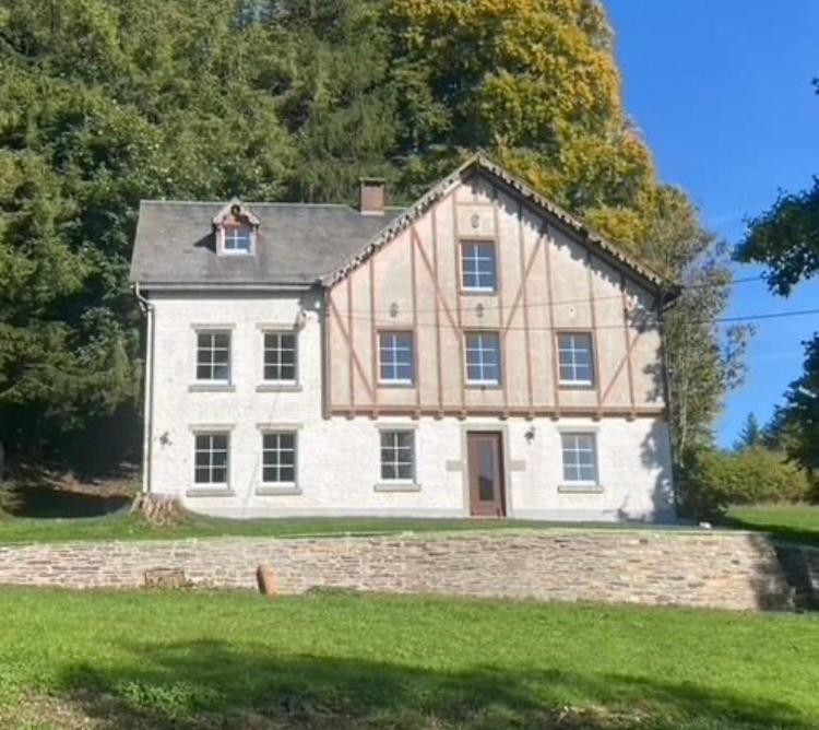 a large white house with a stone wall at La Futaie de Chabrehez- maison typique ardennaise in Houffalize