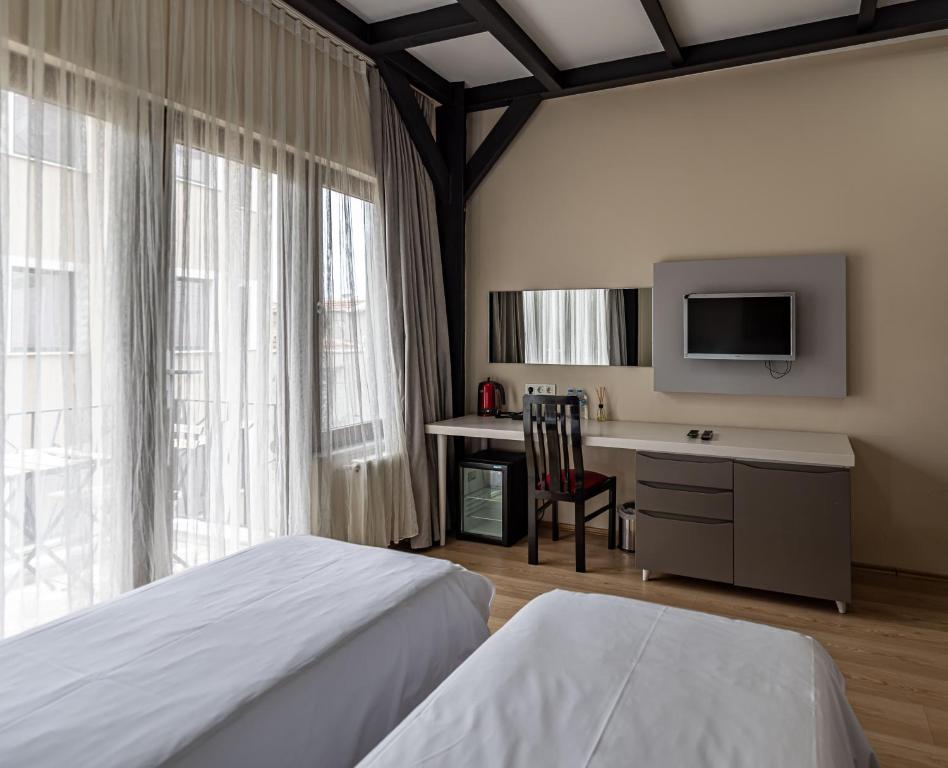 a bedroom with two beds and a desk and a tv at Calanthe Residence in Istanbul