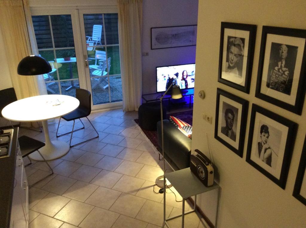 een woonkamer met een tafel en een tv aan de muur bij Oans Thuus in Ballum