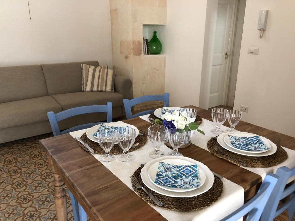 een houten tafel met borden en wijnglazen erop bij Antica Casa del Pozzo in Manduria