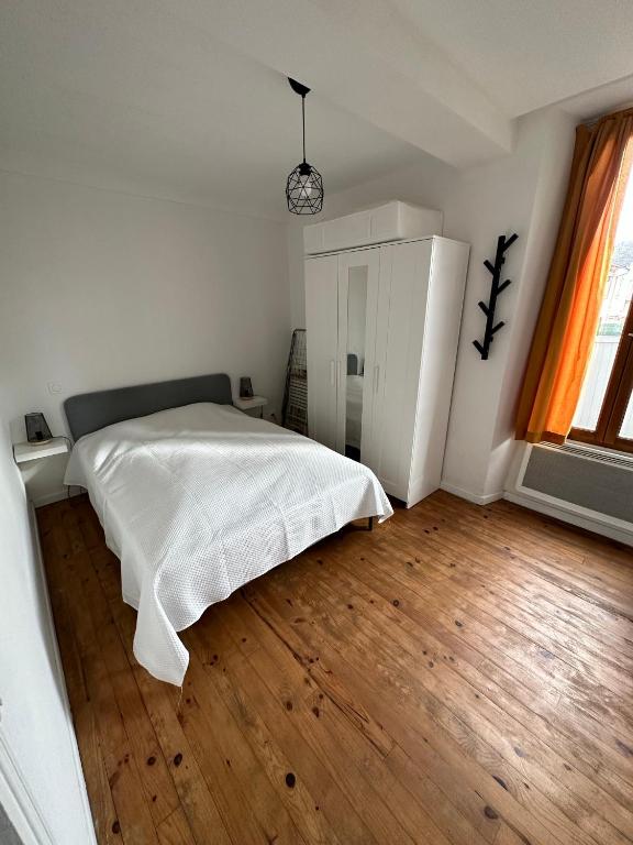 1 dormitorio con cama blanca y suelo de madera en Joli appartement proche centre ville, thermes, Aquensis en Bagnères-de-Bigorre