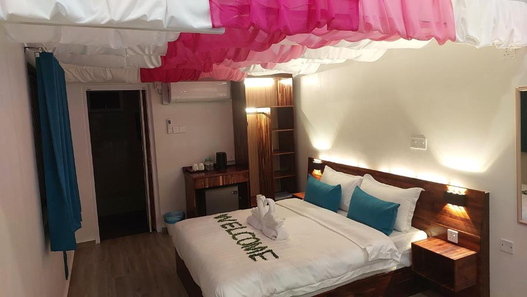 a bedroom with a large bed with blue and pink curtains at Coastal Bay Staycation in Dungun