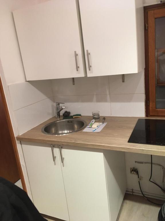 uma cozinha com armários brancos e um lavatório em Loué petit studio maisonnette em Marselha