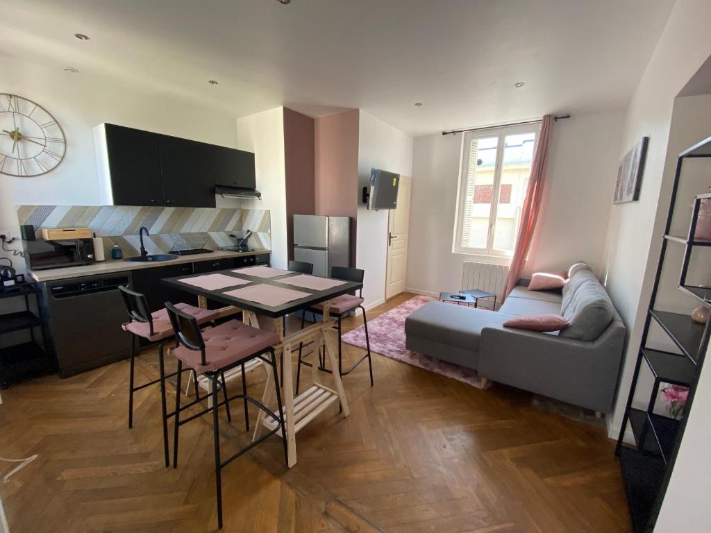 a kitchen and living room with a table and a couch at Pink Cosy in Louviers