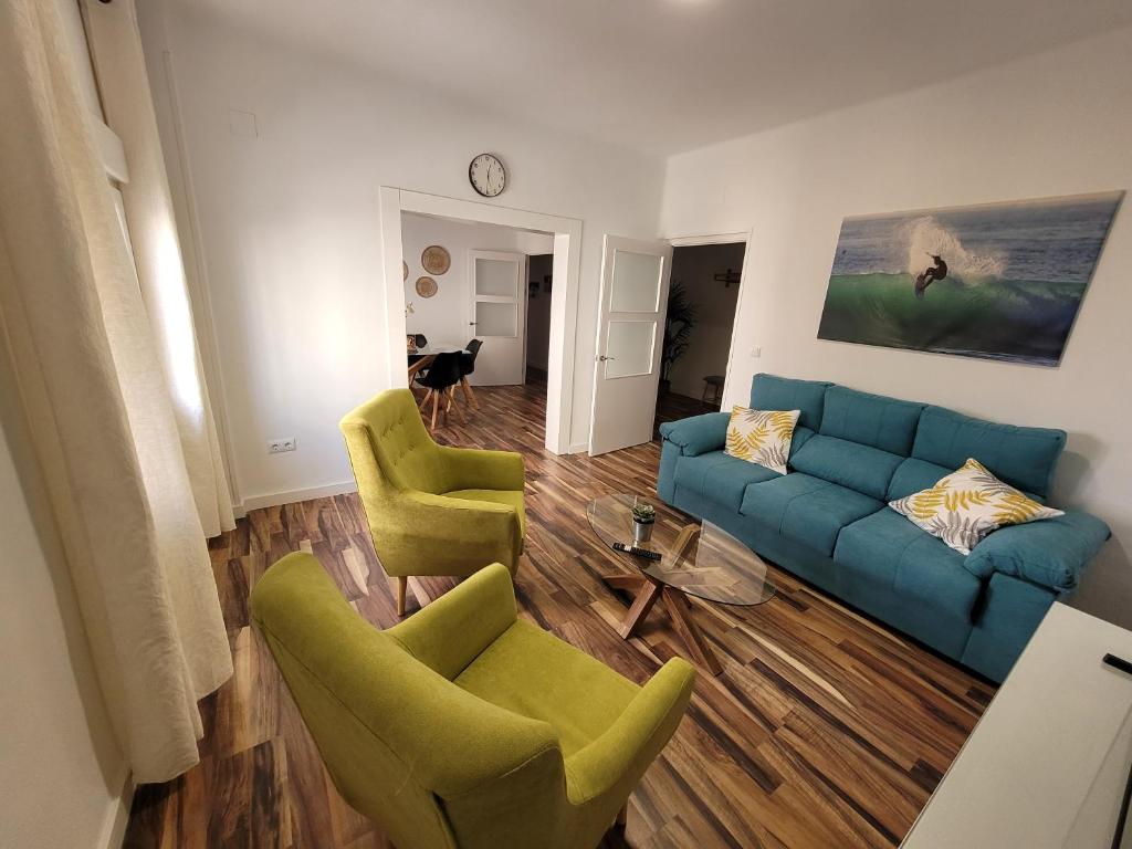 sala de estar con sofá azul y 2 sillas verdes en La Playita Santa María Beach, en Cádiz