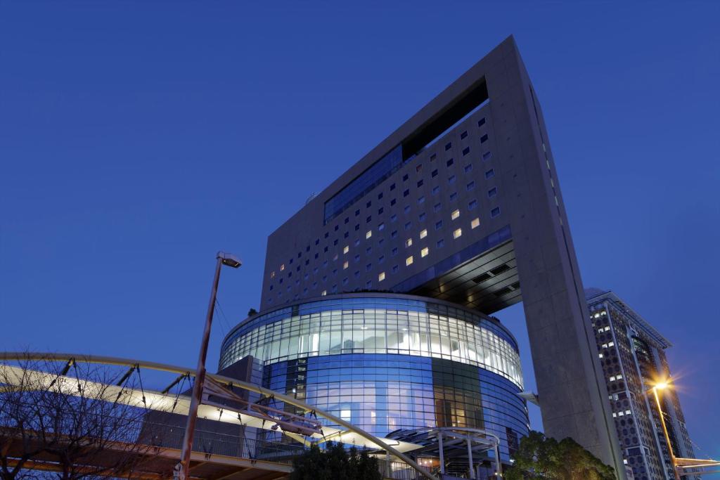 um edifício alto com uma fachada de vidro ao anoitecer em The Mark Grand Hotel em Saitama