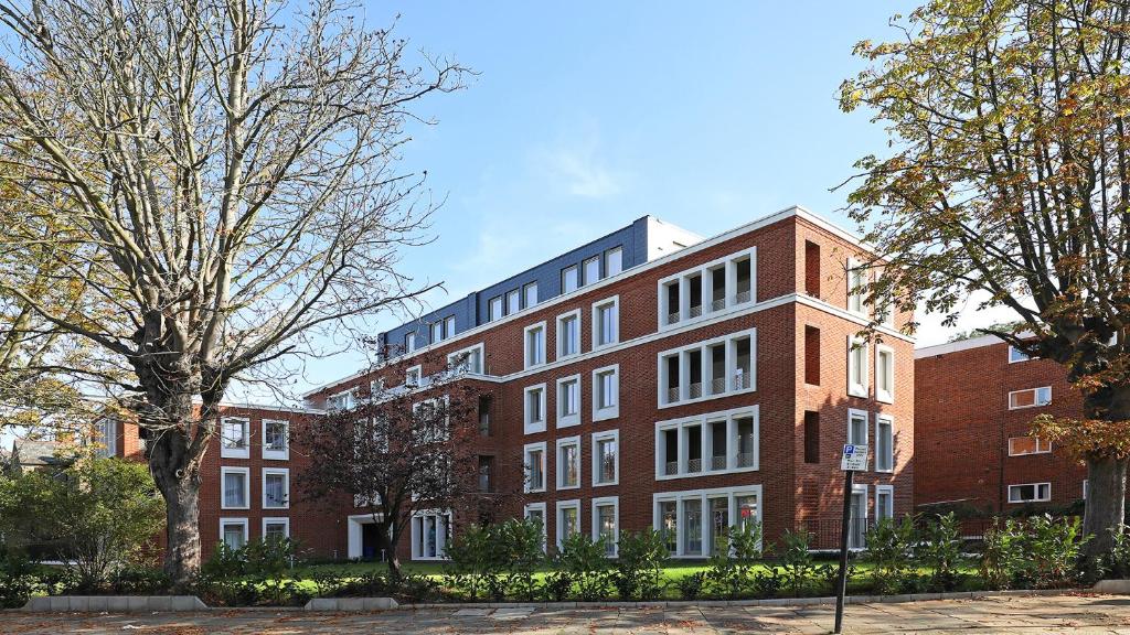 a red brick building with trees in front of it at Stunning apartment building, walking distance to Ealing Broadway tube! in Ealing