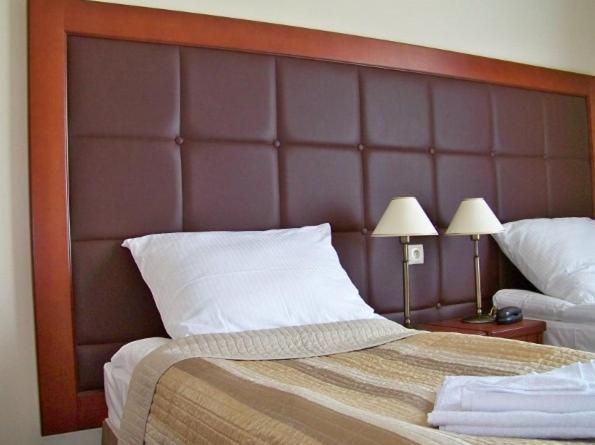a bedroom with a large wooden headboard and two lamps at Hotel Gniecki Gdansk in Przejazdowo