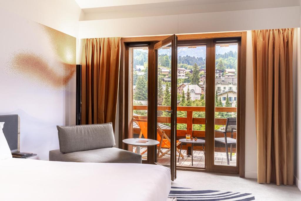 Novotel Megève Mont-Blanc في ميجيف: غرفه فندقيه بسرير وشرفه