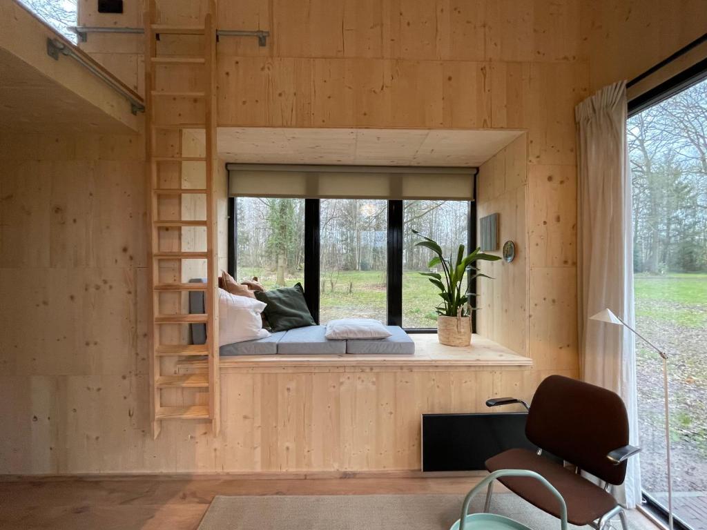 een persoon op een bed in een kamer met een raam bij Buitenplaats Vinckeboom in Diepenheim