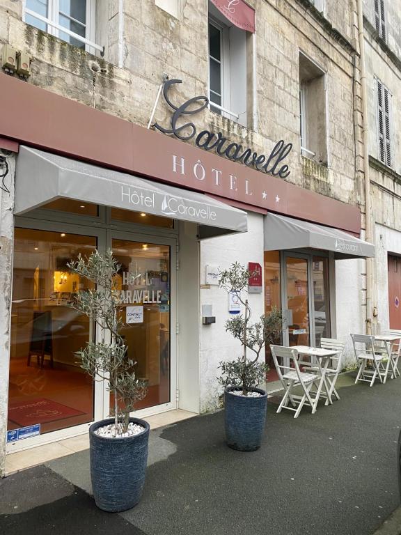 ロシュフォールにあるHôtel Caravelle Contact Hôtelの建物前のテーブルと椅子の店