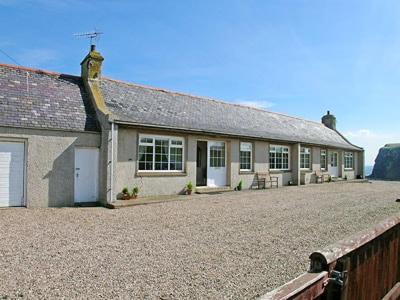 una casa con una entrada de grava delante de ella en Mill Shore Cottage - 26817, en Pennan