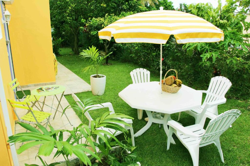 una mesa blanca y sillas con sombrilla en Eden Part' - Appartement avec jardin privé à Baie-Mahault, en Baie-Mahault