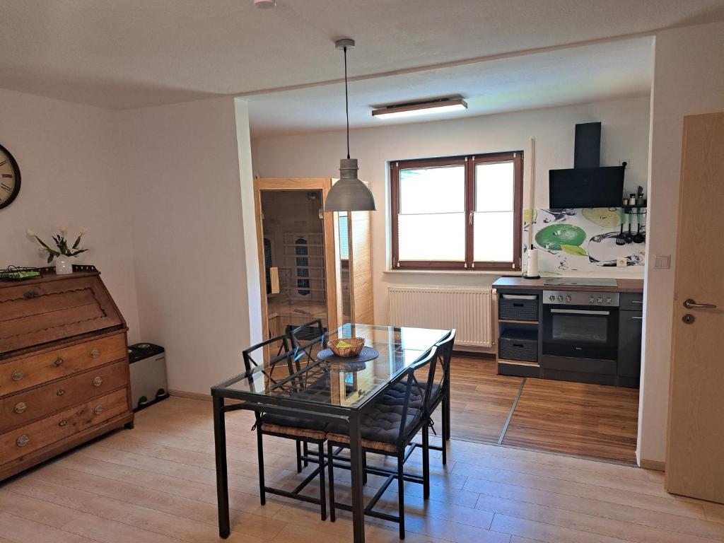 cocina con mesa de cristal y sillas en una habitación en Hof Helmenhube 2, en Gammelsbach