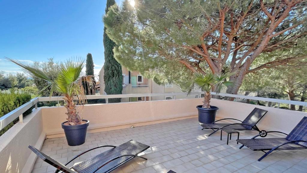 d'une terrasse avec des chaises et des palmiers sur un balcon. dans l'établissement Les Coteaux de la Nartelle, à Sainte-Maxime