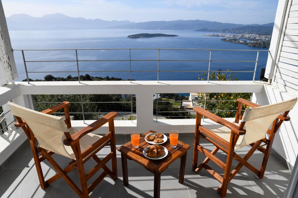 un balcón con 2 sillas y una mesa con comida. en Villa Veranda Agios NIkolaos (suite), en Agios Nikolaos