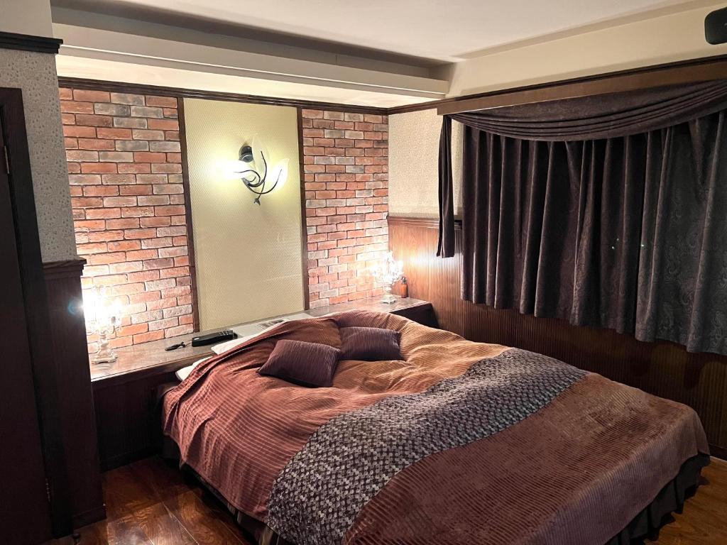 a bedroom with a bed and a brick wall at ホテル 夢街道 