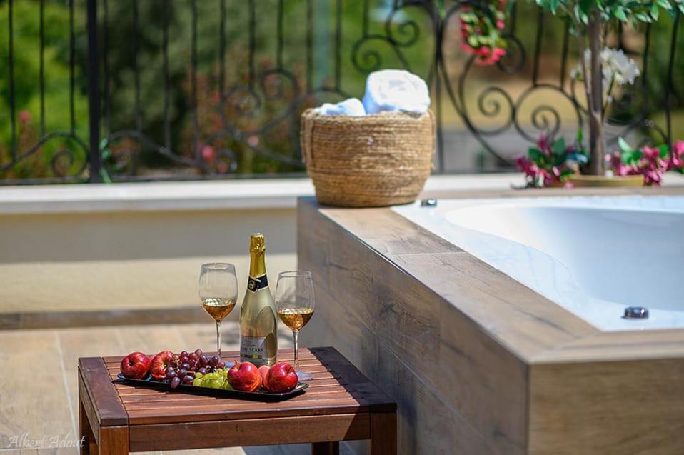 zwei Gläser Wein und ein Tablett mit Obst neben einer Badewanne in der Unterkunft סוויטת בוסתן ונחל in Kibbuz Dafna