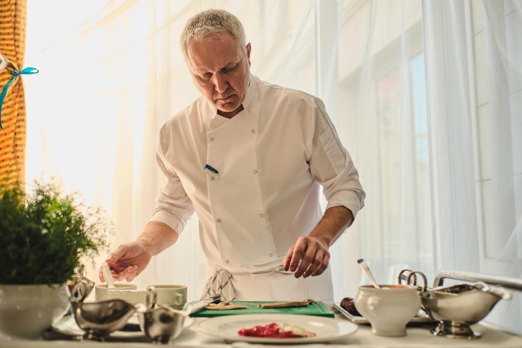 a chef standing in a kitchen preparing food at Hotel Exel in Amstetten