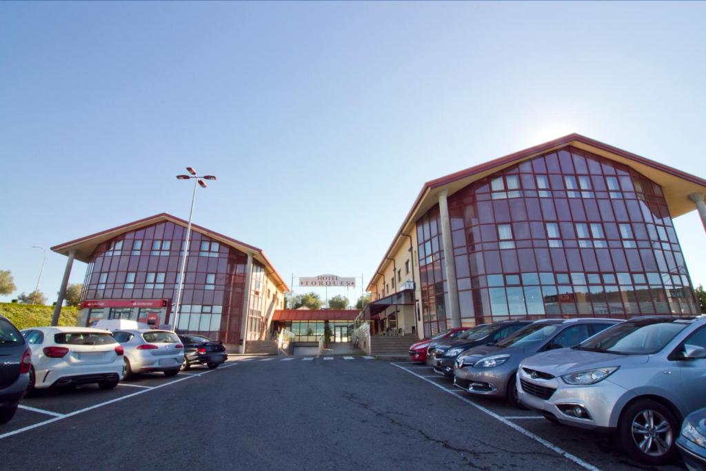 a parking lot with cars parked in front of two buildings at Hotel Torques in A Coruña