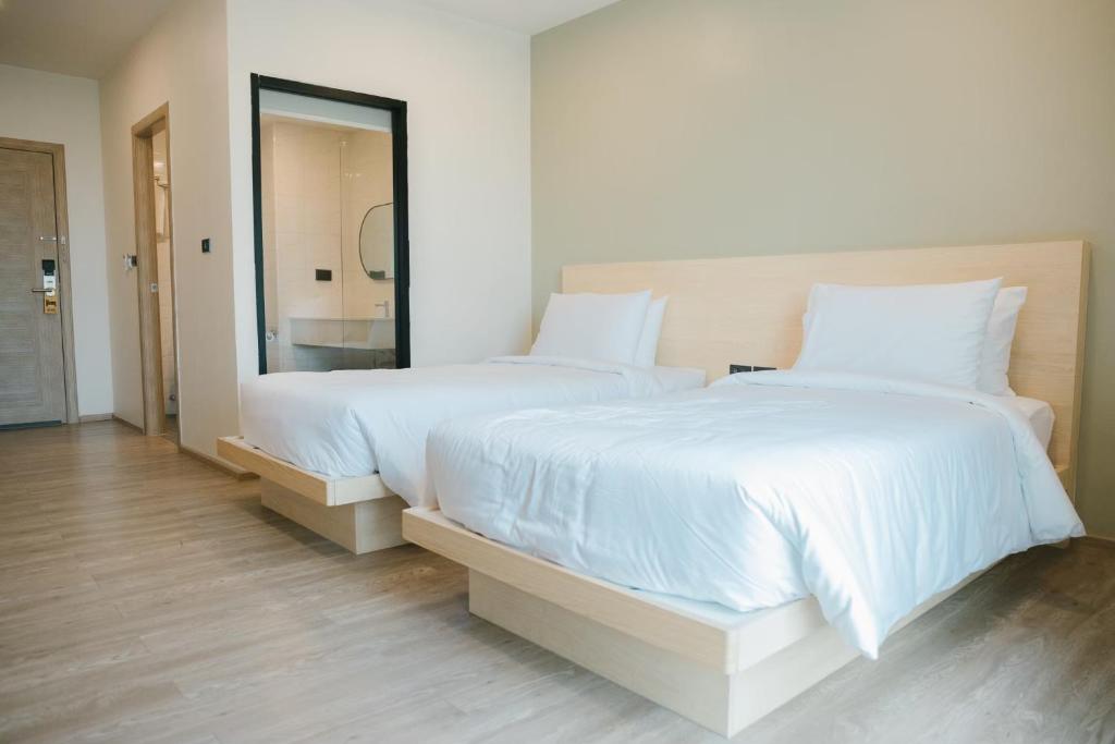 1 dormitorio con 2 camas con sábanas blancas y espejo en Mayuu Ayutthaya Hotel en Ban Ko Rian