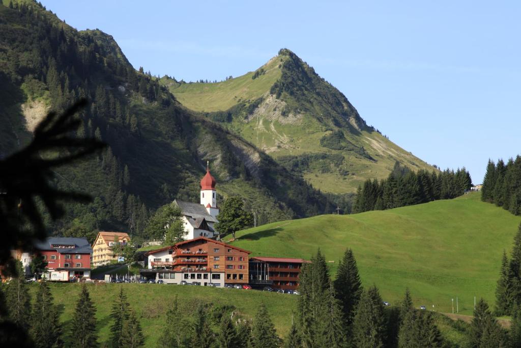 un village sur une colline avec une montagne en arrière-plan dans l'établissement Boutique Hotel die Mittagspitze Superior, à Damüls