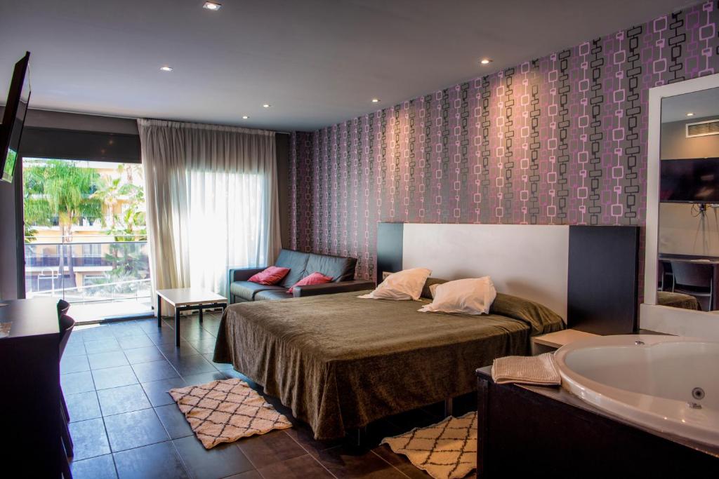 リョレート・デ・マルにあるHotel Acacias Suites & Spaのベッドとバスタブ付きのホテルルームです。
