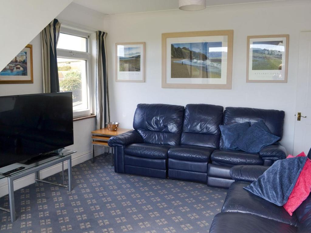 a living room with a leather couch and a flat screen tv at West Park in Hope Cove